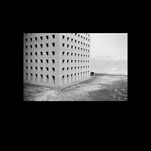 Black and white photo of a large, geometric building with small windows.