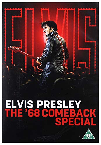 Elvis Presley in a black leather suit playing guitar before a red neon sign.