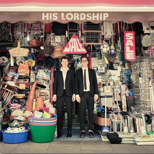 Album cover: two men in suits stand before a cluttered shopfront.