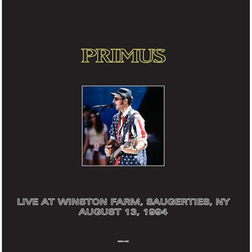 Vinyl cover featuring Les Claypool in a flag shirt performing on stage at concert.