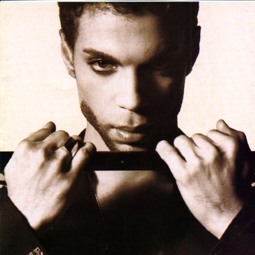 Close-up portrait of Prince in black and white, pulling at his collar.