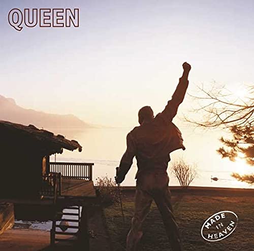 Silhouette of a man with arm raised standing by a lake at sunset.