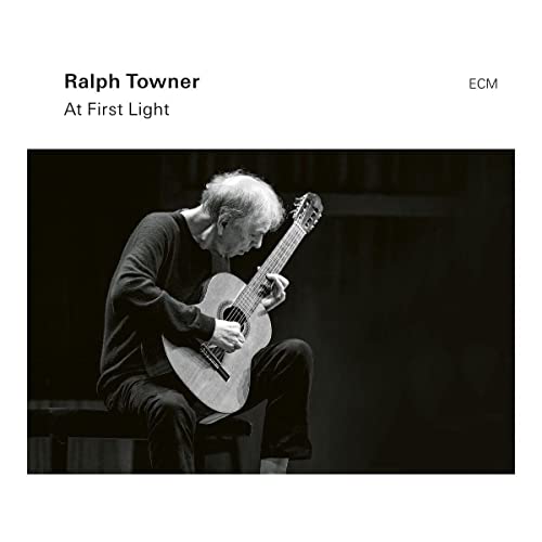 Black and white photo of Ralph Towner playing an acoustic guitar on stage.