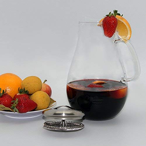 Glass pitcher filled with red liquid, garnished with fruit, and a strainer.