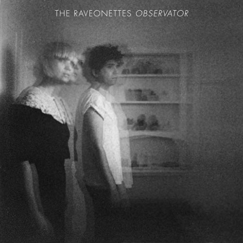 Black and white blurry photo of two people standing in front of a shelf.