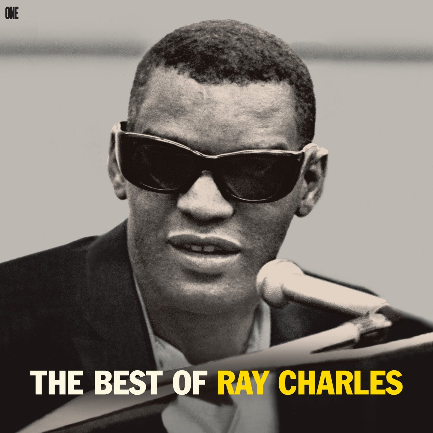 Black and white portrait of Ray Charles wearing sunglasses, singing into a microphone.
