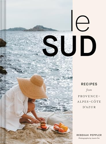 Cookbook cover with coastal scene, straw hat, and fresh produce.
