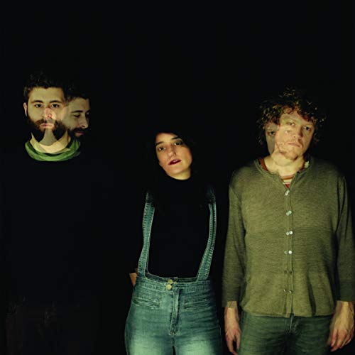 Three people stand against a black background with a double exposure photographic effect.