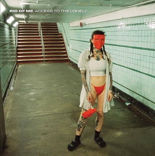 Woman with red face and tattoos stands in a subway tunnel.