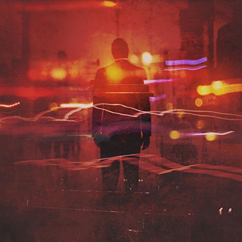 Silhouetted figure stands amidst blurred city lights, predominantly red tones.