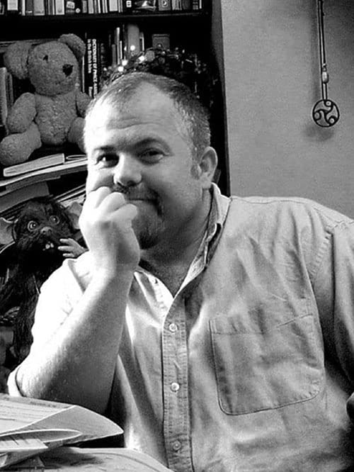 Black and white portrait of a man with a book and teddy bear.