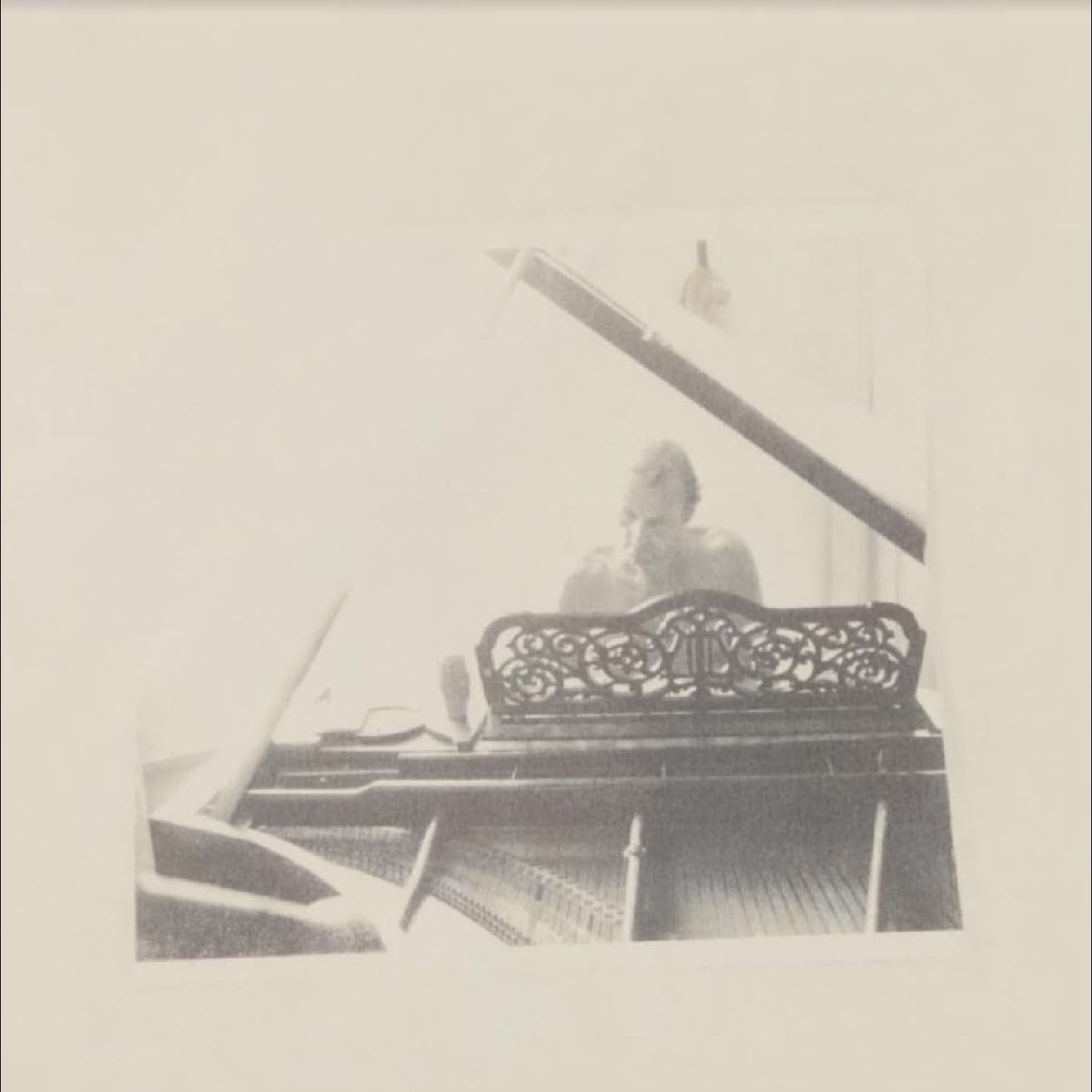 Black and white photo of a man at a piano, blurred image.