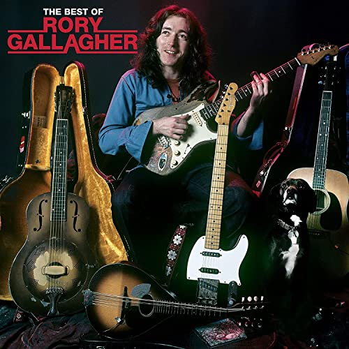 Rory Gallagher playing guitar surrounded by his instruments and a dog against black background.
