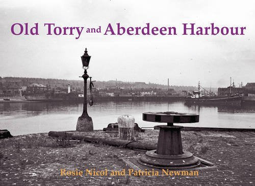 Black and white harbour scene with lamp post and bollards.