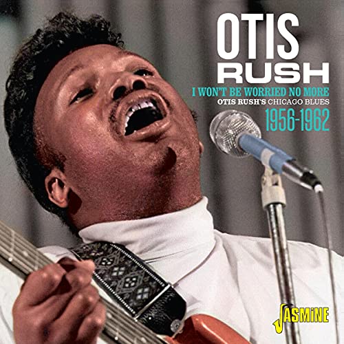 Otis Rush singing into a microphone while playing an electric guitar.
