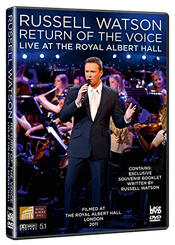 Russell Watson singing into a microphone on stage with an orchestra in the background.