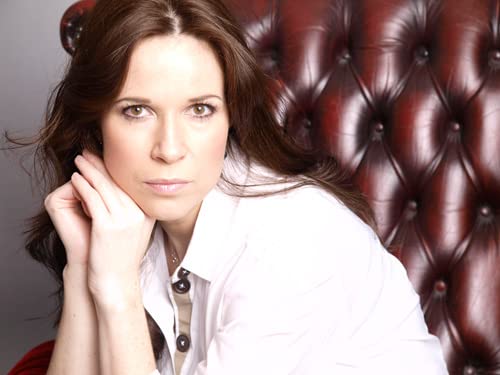 Woman with long brown hair posing in front of a red leather chair.