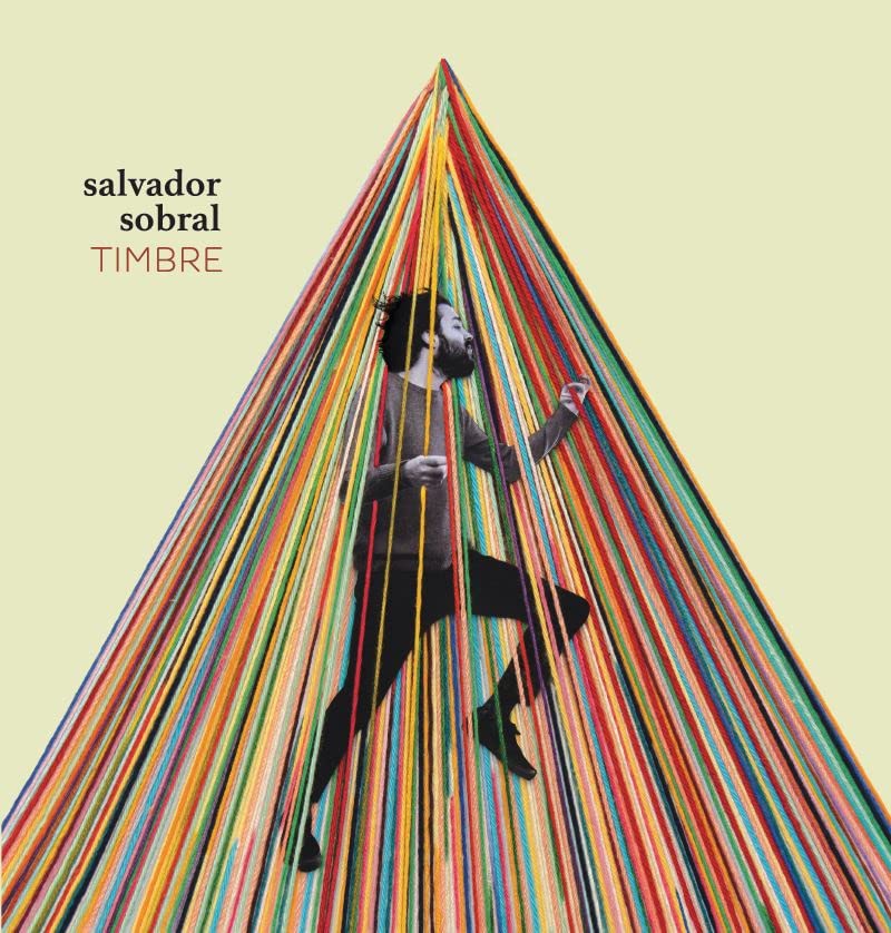 Album cover: Salvador Sobral stands amidst a colorful, cascading yarn structure.