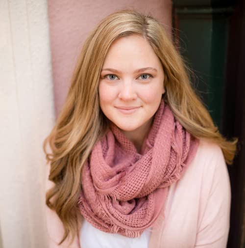 Young woman with long wavy brown hair and a pink scarf.
