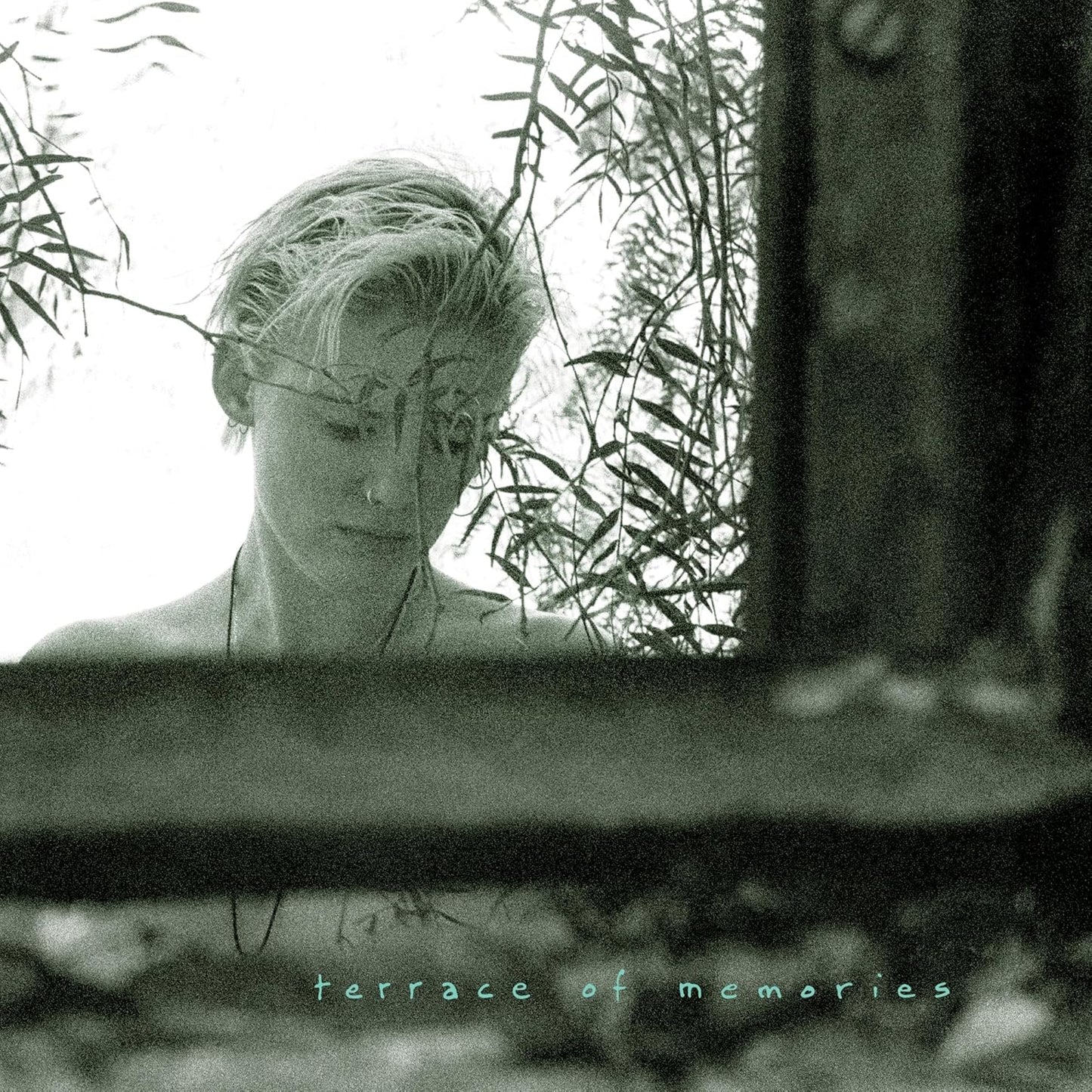 Grainy black and white portrait of a person amidst foliage.