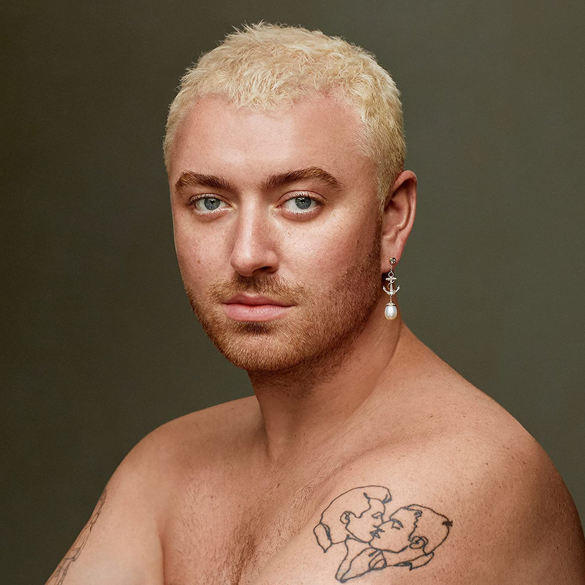 Sam Smith portrait, blonde hair, bare chest, and facial tattoos.