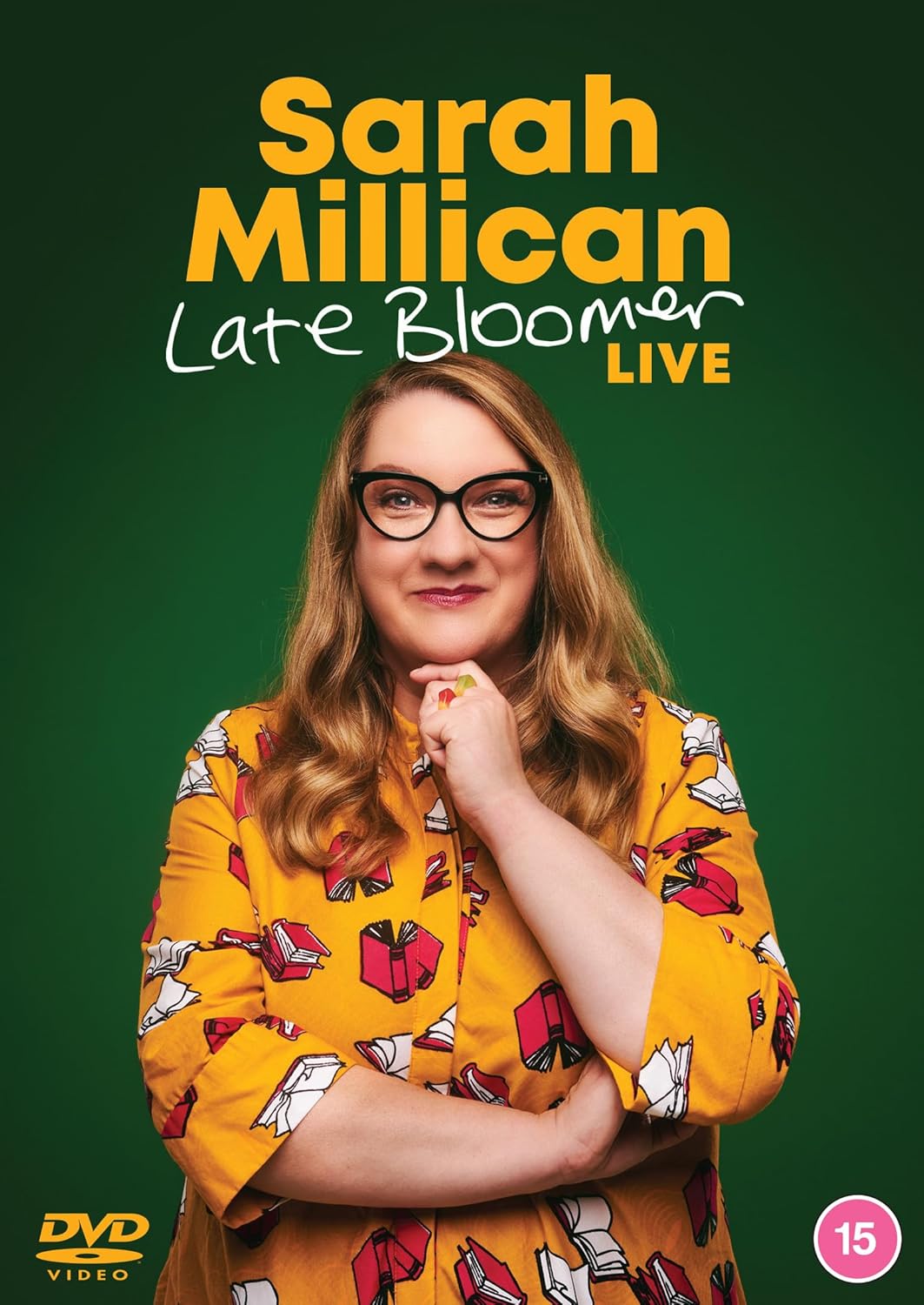 Sarah Millican wearing glasses and a book-print shirt against a green background.