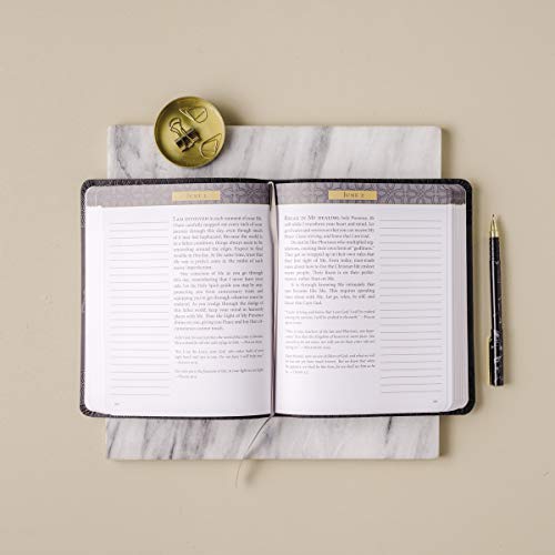 Open black devotional journal with scripture and lined pages, gold clip and pen.