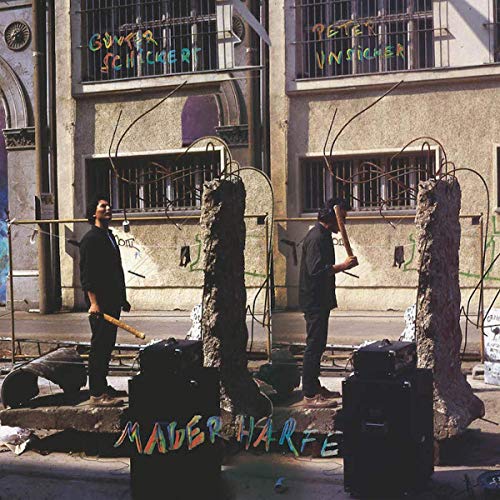 "CD cover showing two men working on metal sculptures in front of a building."