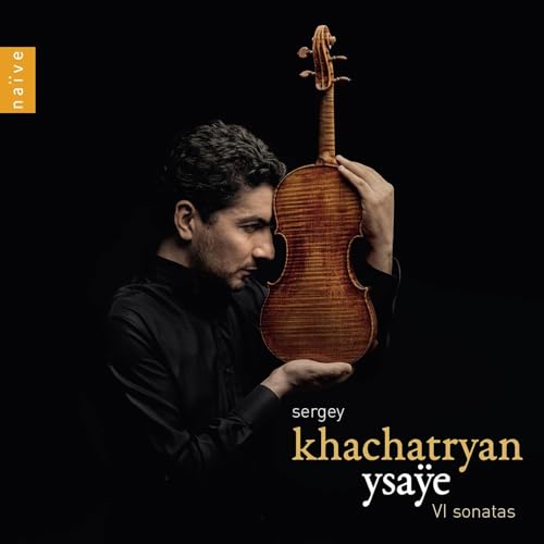 Violinist Sergey Khachatryan holds a violin against a dark background.