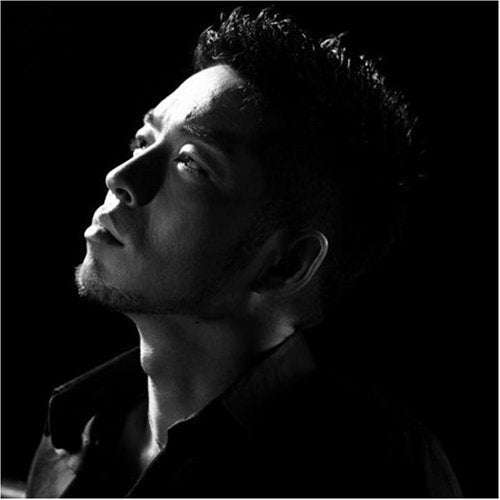 Black and white portrait of a man looking upward against a dark background.