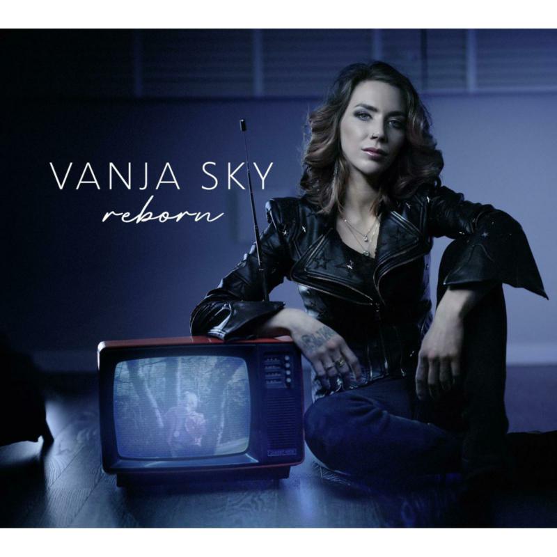 Woman in leather jacket sitting beside a vintage television.