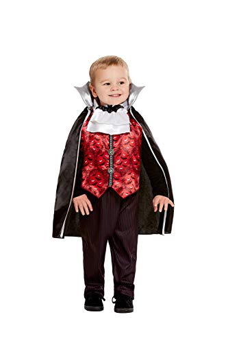 A toddler wearing a vampire costume with a black cape, red vest, and trousers.