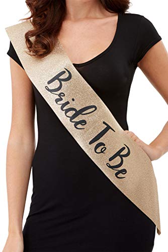Gold glitter "Bride To Be" sash worn across a black dress.