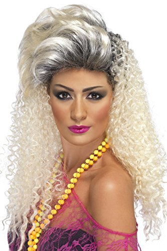 A woman with a blonde, curly wig and dark roots, wearing a pink top and yellow beads.