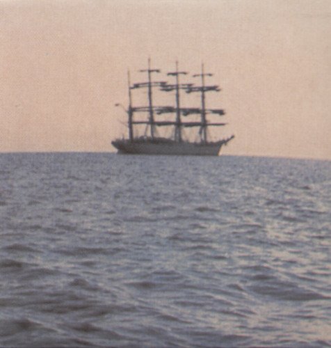 Tall ship sailing on a calm sea, hazy pink and blue tones.
