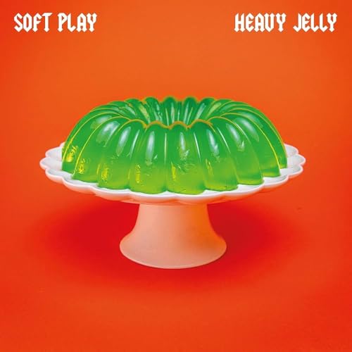 Green gelatin dessert on a white cake stand against an orange background.