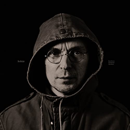 Hooded man with glasses, album cover for “Solit - Bus Driver Immigrant Mechanic.”