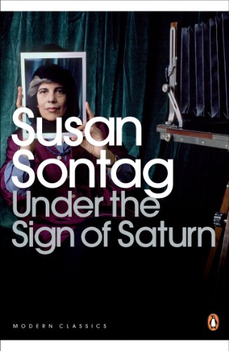 Susan Sontag holds a portrait of herself in front of her face near a camera.