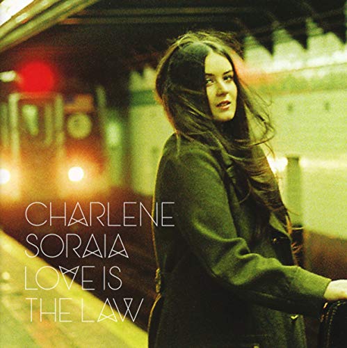 CD cover featuring a woman in a coat, blurred city background.