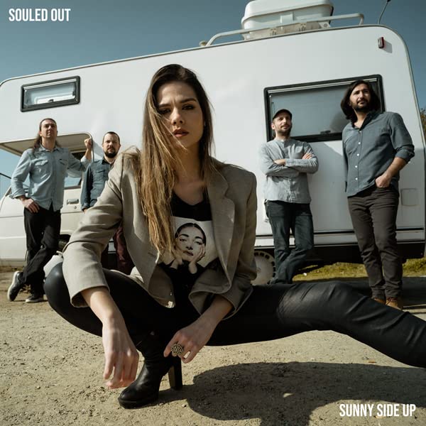 Album cover featuring a band posing in front of a vintage RV.