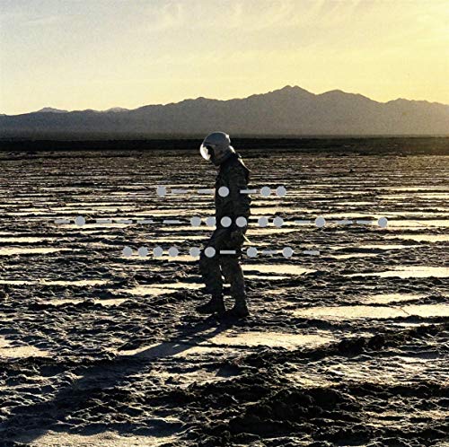 Figure in helmet walking across cracked earth towards distant mountains.