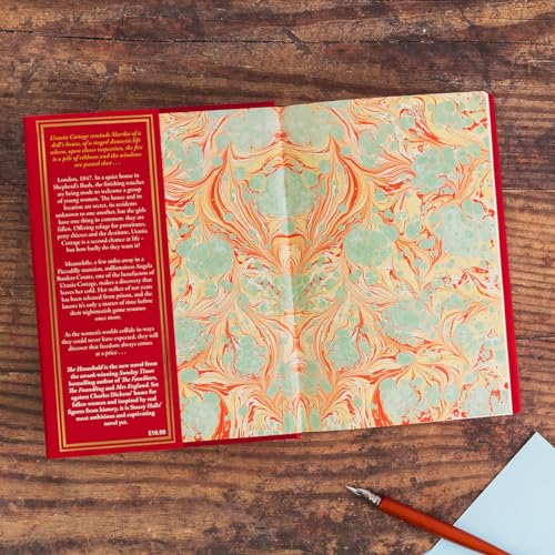 Open book with marbled endpapers and red cover, resting on wood.