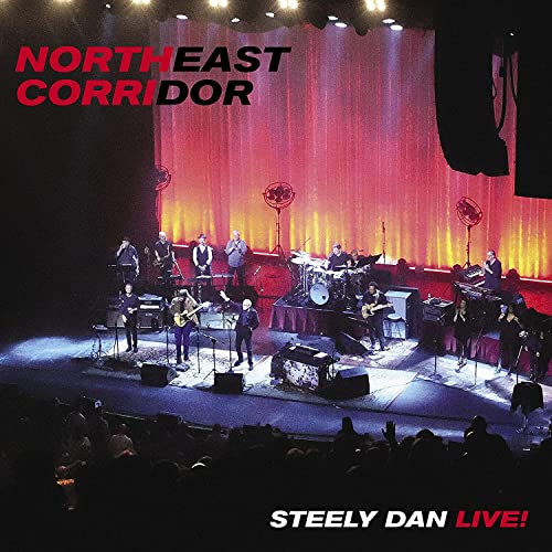 Steely Dan live concert stage with band members performing, red title text.