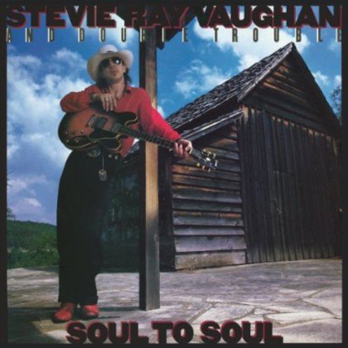 Stevie Ray Vaughan album cover featuring a man with a guitar by a wooden shed.