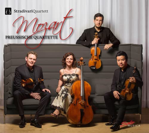 Stradivari Quartet posing with violins and a cello on a grey couch.
