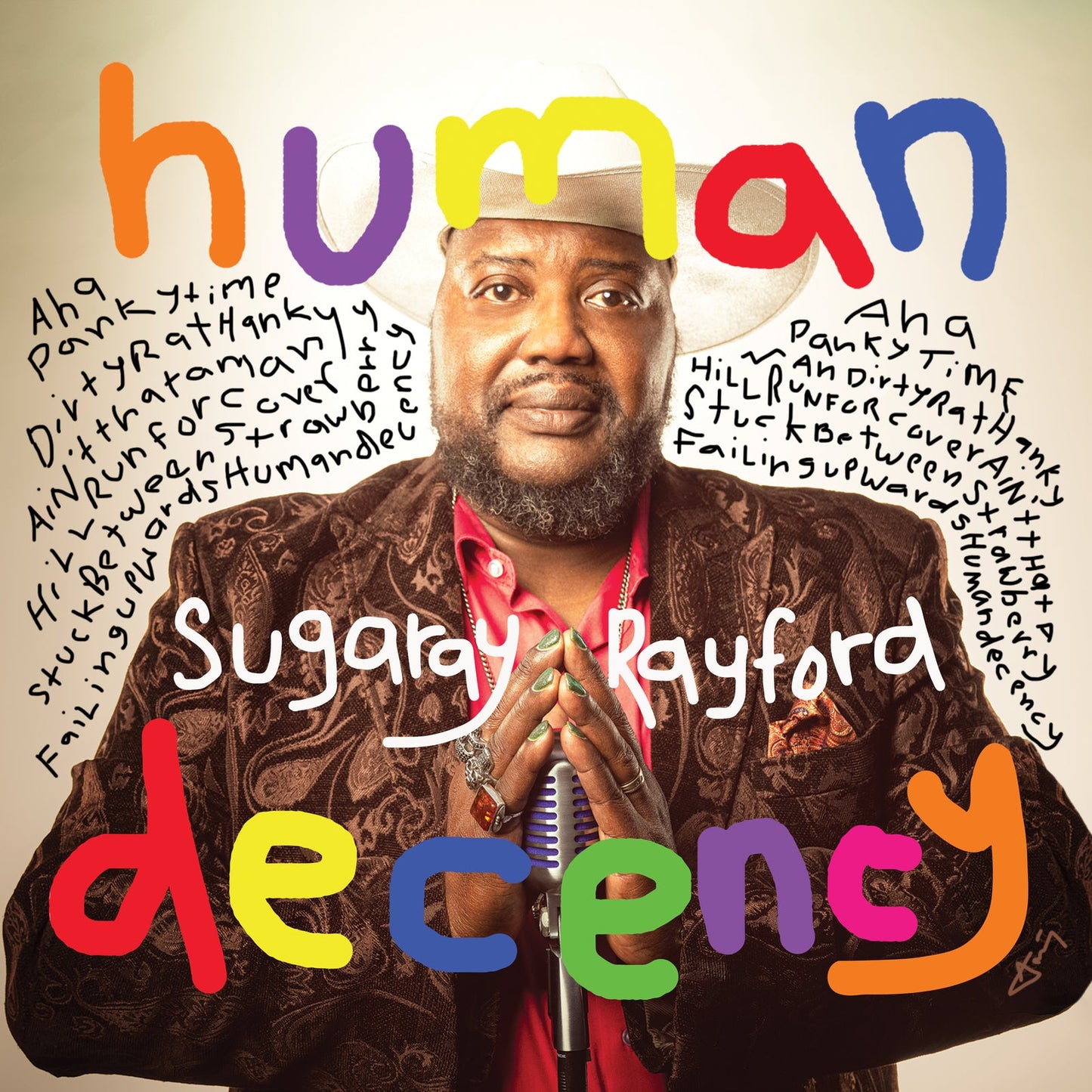 Sugaray Rayford wearing a cowboy hat and paisley jacket, holding a vintage microphone.