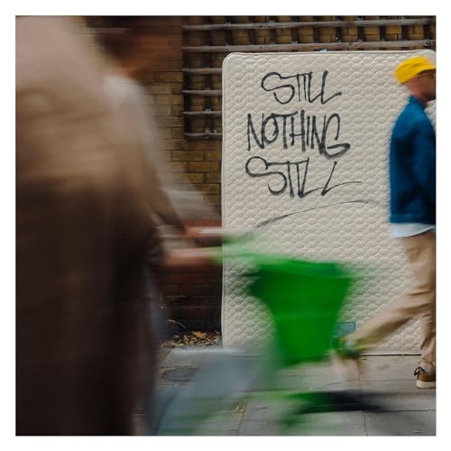 Vinyl album cover with graffiti text on a mattress, blurred figures.
