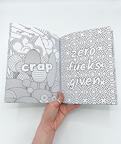 A hand holds an open coloring book with pages featuring geometric patterns and text.
