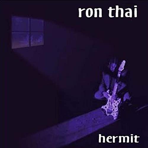 A person playing a guitar in a dark, purple-lit room with a window.
