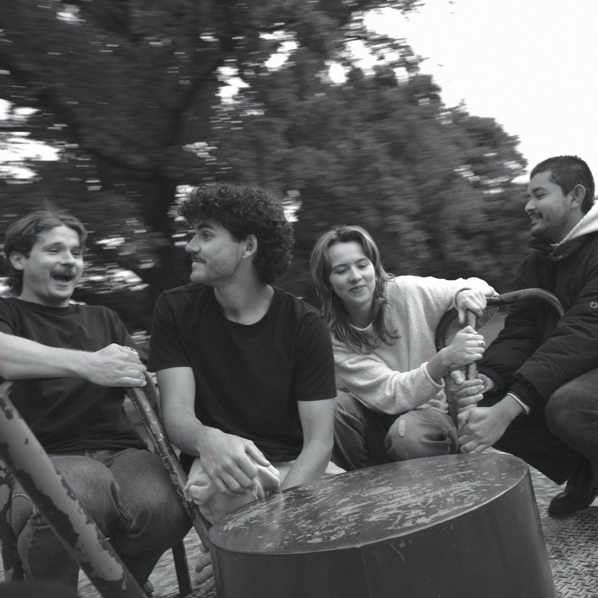 Black and white photo of four people seated outdoors.